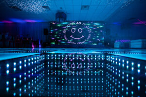 Guests dancing on a colorful LED lighted dance floor at an evening event.