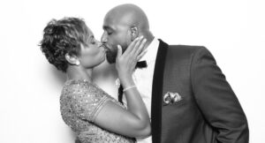 Couple sharing a kiss inside a decorated photo booth at a party.