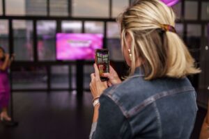 A woman filming her karaoke event for marketing as an event trend in 2024.