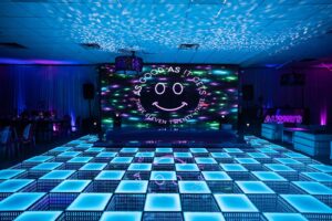 Elegant stage setup for a Bat Mitzvah with DJ equipment and lighting.