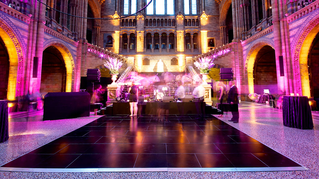 Elegant custom dance floor at a wedding with slick black flooring and custom lighting