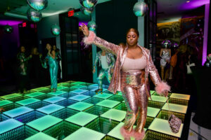 Woman on the dance floor in a glittery jacket and pants.