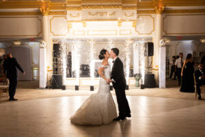 Bride and groom sharing a kiss with sparklers illuminating the background during their wedding reception.