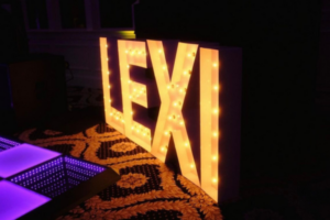 LED life-size letters spelling "Lexi" illuminated at a Sweet Sixteen party, adding a personalized element.
