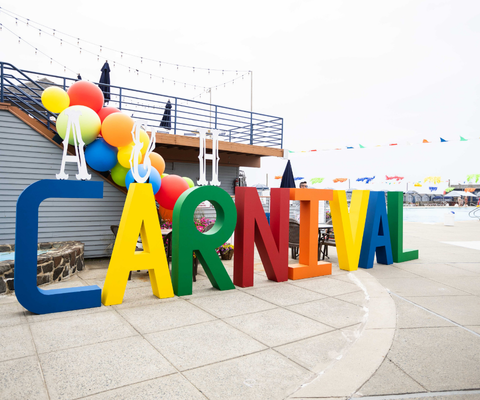A carnival-themed setup for a corporate event, featuring colorful balloons and bold signage, offering a unique event theme idea.