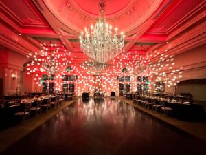 Custom lighting design illuminating a corporate gala event space with chandeliers and colorful spotlights.