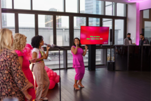 Three women sing at a karaoke party, enjoying interactive entertainment with lyrics displayed on a large screen.