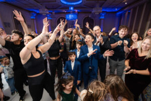 Dignified guests dance and celebrate with joy in the Bat Mitzvah ceremony, accompanied by melodies that create a background of glee.