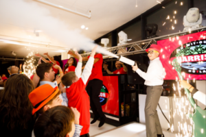 Bar Mitzvah boy firing a CO2 cannon surrounded by friends, LED lighting, and a DJ booth.