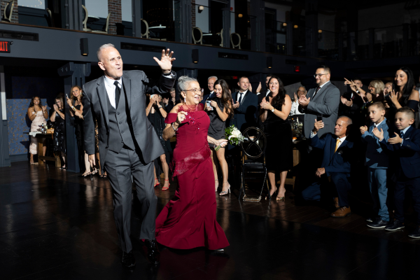 Parents walking into a wedding reception, surrounded by cheering guests, highlighting how entrance timing impacts the atmosphere.