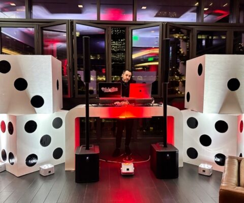 DJ stage with dice speakers and red lighting.