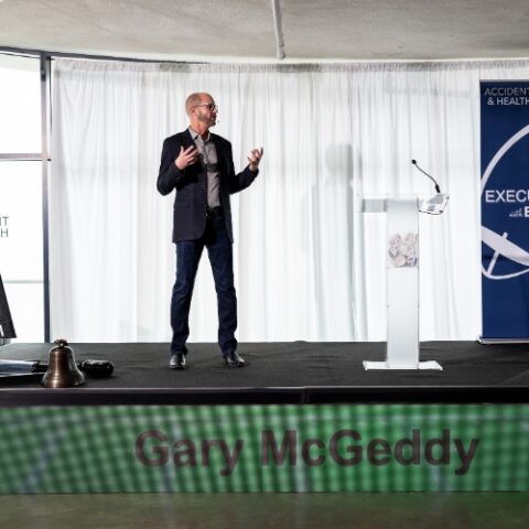 Speaker on stage with LED video wall display.