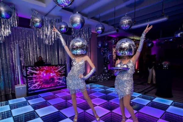 Disco-themed performers on an LED dance floor.