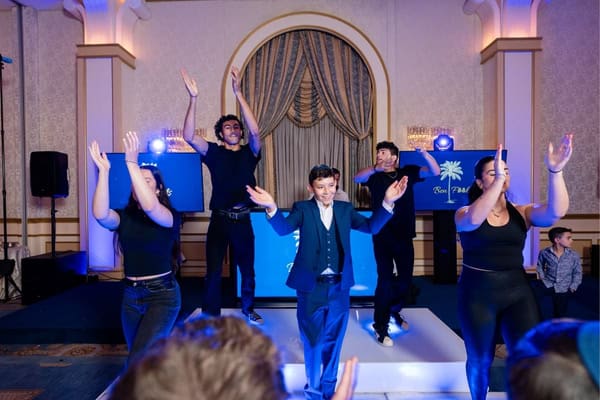A DJ leading an energetic Mitzvah celebration with dancers.