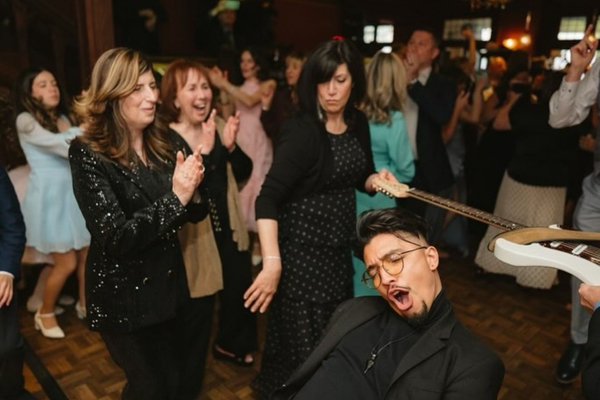 Guest limbos under guitar at wedding