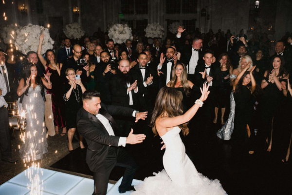 Bride and groom dancing surrounded by cheering guests