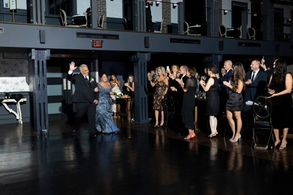 Parents entering the wedding reception as guests cheer